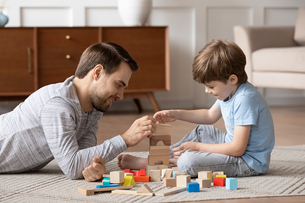 Young dad play with building bricks with small son